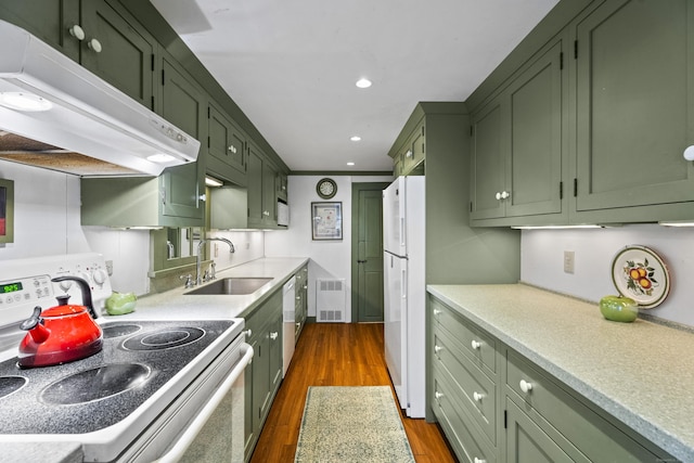 kitchen with stove, dark wood-type flooring, green cabinets, white refrigerator, and sink