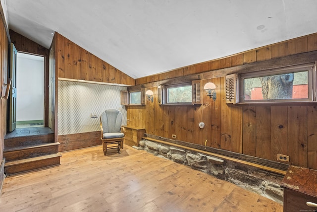 sitting room with lofted ceiling, light hardwood / wood-style floors, and wooden walls