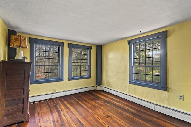 spare room with plenty of natural light, dark hardwood / wood-style flooring, and a baseboard heating unit