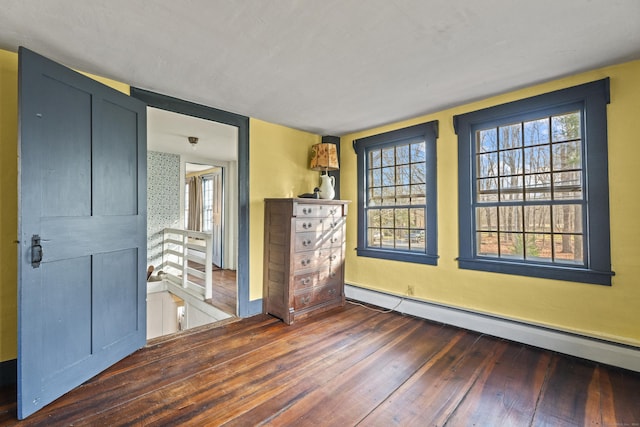 unfurnished bedroom with a baseboard radiator and dark hardwood / wood-style floors