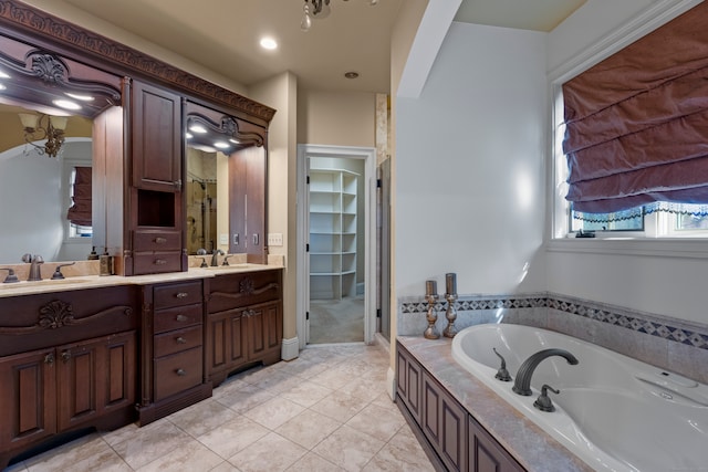 bathroom with tile patterned floors, tiled bath, and vanity