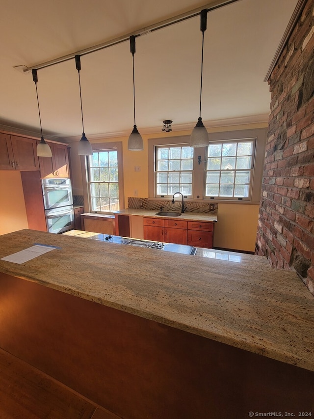 kitchen featuring light stone countertops, sink, rail lighting, and pendant lighting