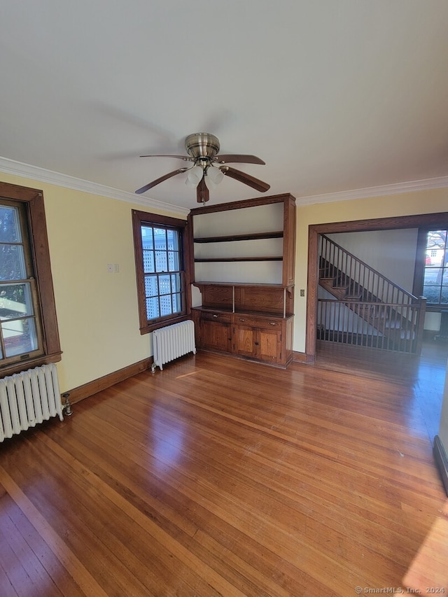 unfurnished living room with radiator heating unit, ceiling fan, ornamental molding, and hardwood / wood-style floors