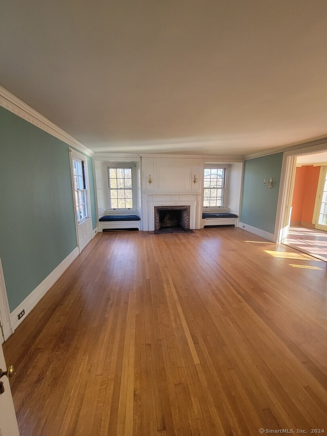 unfurnished living room featuring a fireplace, light hardwood / wood-style flooring, and ornamental molding