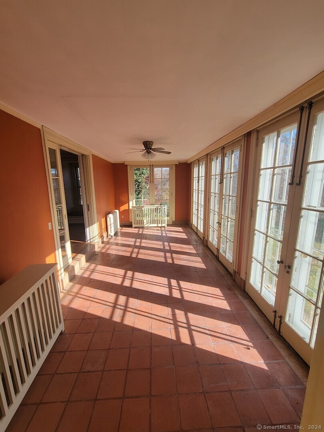 unfurnished sunroom with ceiling fan, radiator heating unit, and french doors