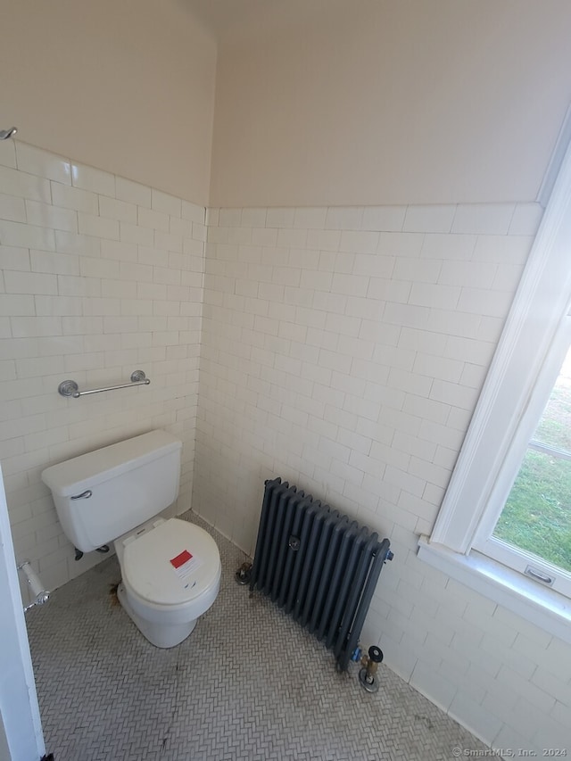 bathroom with tile patterned flooring, toilet, tile walls, and radiator