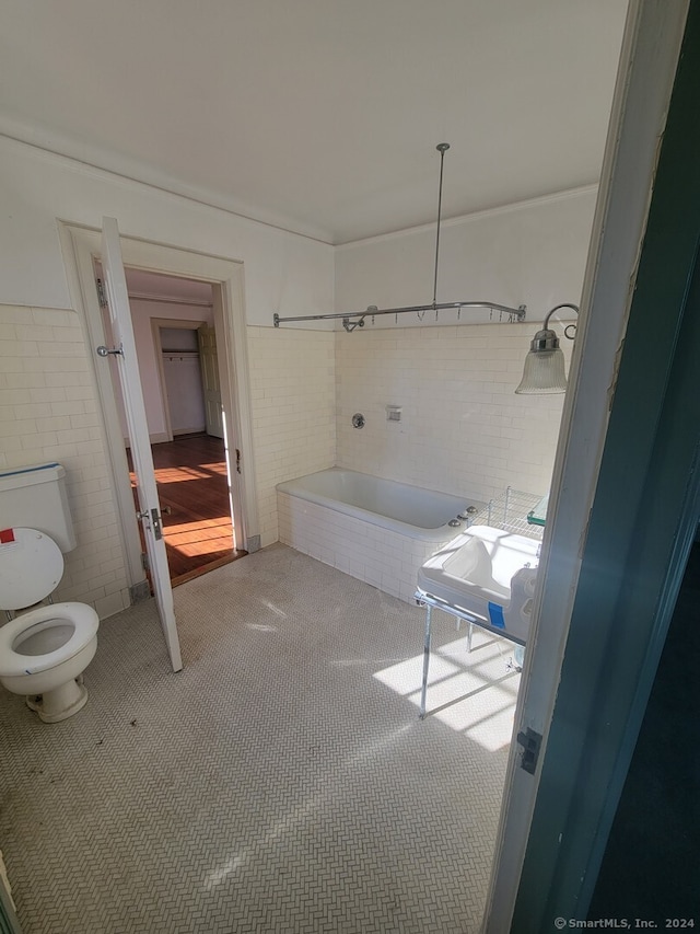 bathroom with toilet, tile walls, and a tub