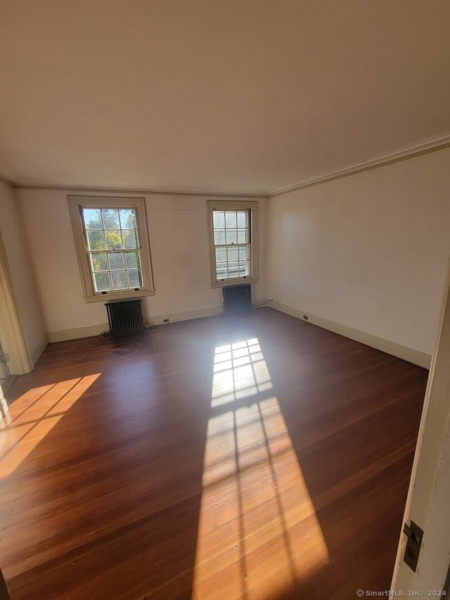 spare room featuring dark hardwood / wood-style flooring and radiator heating unit