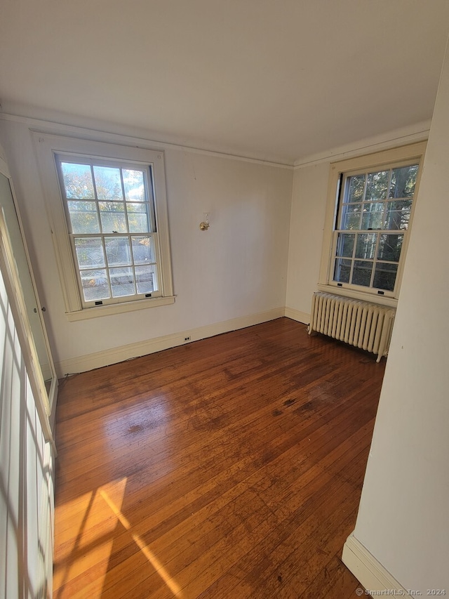 spare room with dark hardwood / wood-style flooring and radiator heating unit