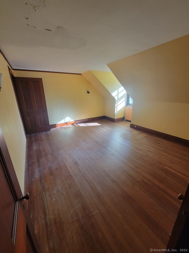 additional living space with wood-type flooring and vaulted ceiling