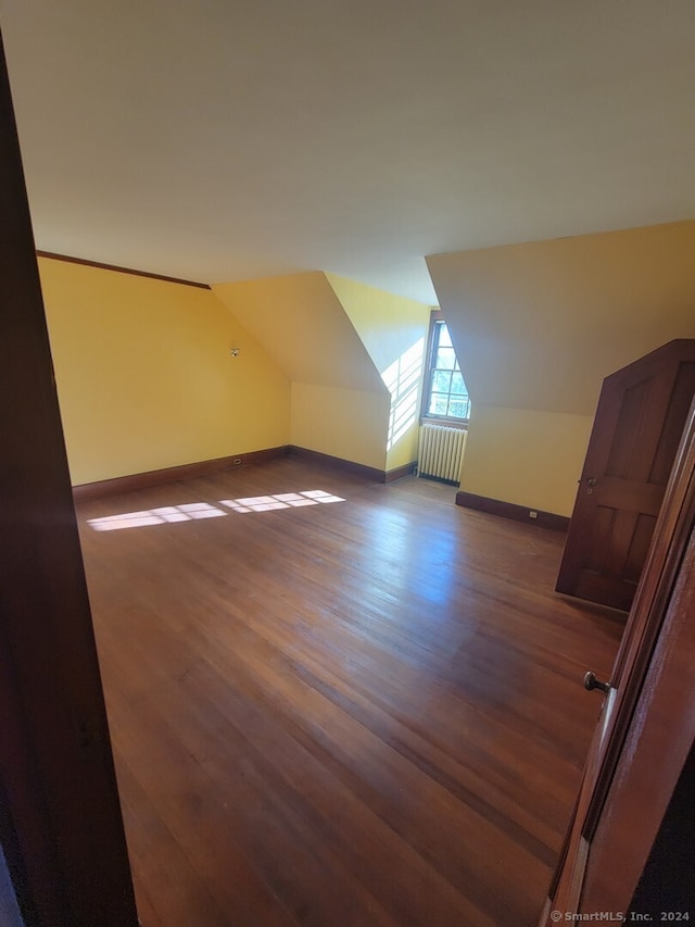 additional living space with hardwood / wood-style floors, radiator heating unit, and vaulted ceiling