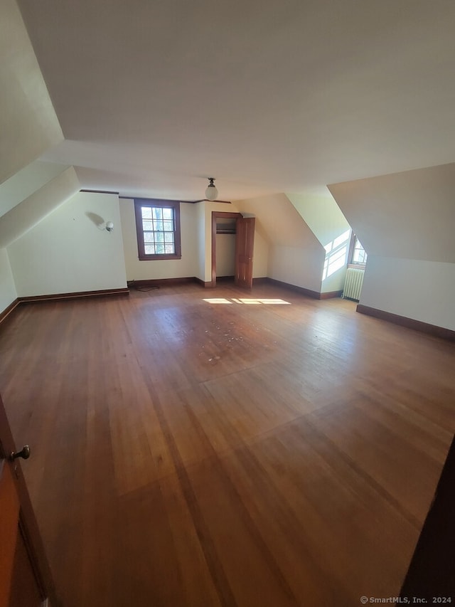 bonus room with lofted ceiling, wood-type flooring, and radiator