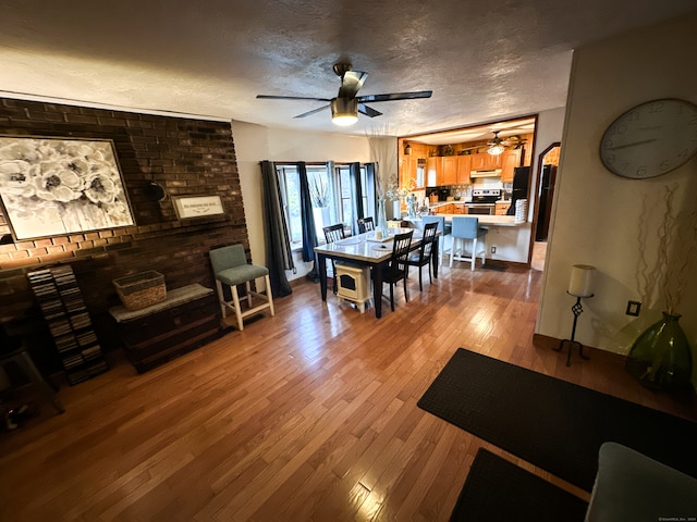 dining room with ceiling fan, a textured ceiling, and light hardwood / wood-style flooring