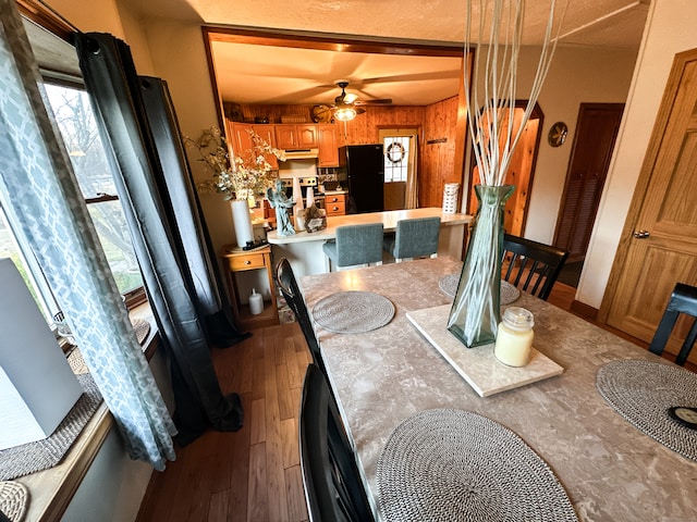 dining area with wood walls, hardwood / wood-style floors, and ceiling fan