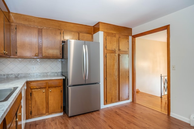 45 Wentworth Dr, East Hartford, CT 06118 - kitchen with freestanding refrigerator, brown cabinets, light wood-style flooring, and decorative backsplash