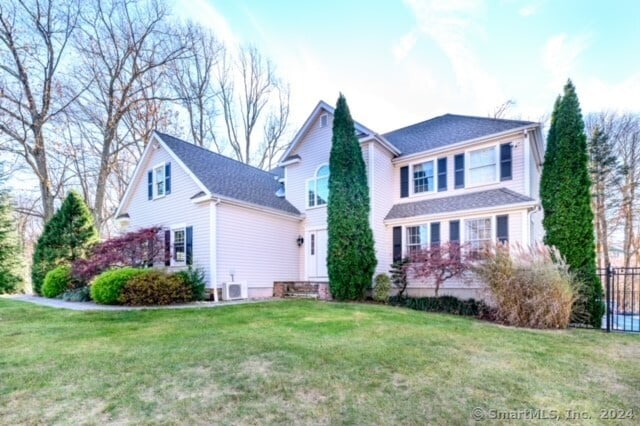 view of front of property featuring ac unit and a front lawn