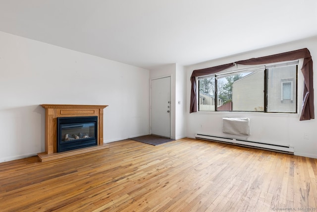 unfurnished living room with a baseboard heating unit and light hardwood / wood-style floors