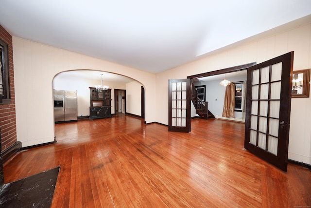 empty room with hardwood / wood-style flooring, a notable chandelier, and french doors