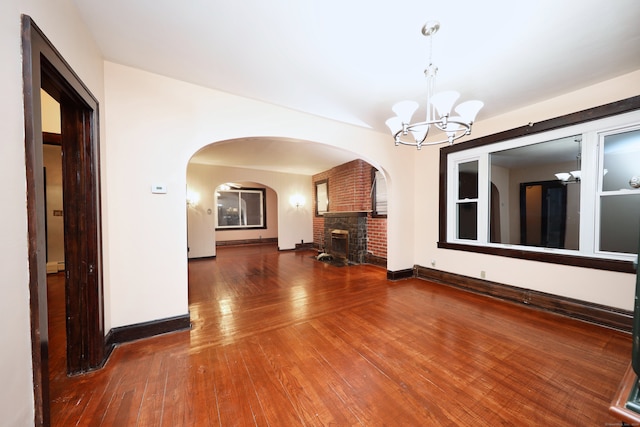 interior space featuring an inviting chandelier, wood-type flooring, and a brick fireplace