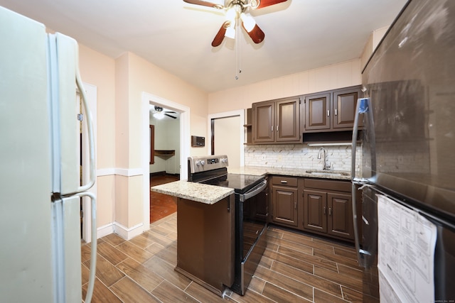 kitchen with dark brown cabinetry, light stone countertops, sink, stainless steel appliances, and tasteful backsplash