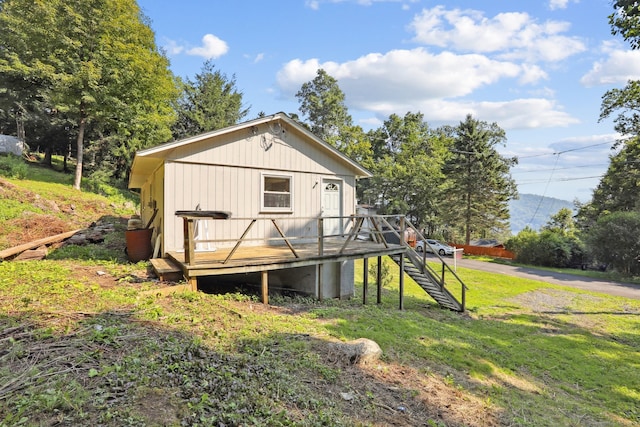 rear view of house with a lawn and a wooden deck