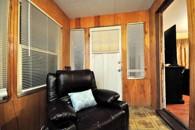 sitting room with tile patterned floors and wood walls