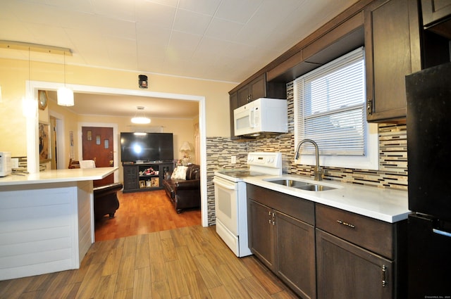 kitchen featuring white appliances, backsplash, sink, hanging light fixtures, and light wood-type flooring