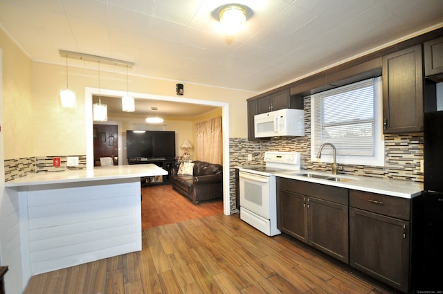 kitchen with white appliances, sink, dark hardwood / wood-style floors, decorative light fixtures, and kitchen peninsula