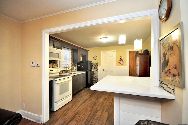 kitchen with sink, dark hardwood / wood-style flooring, kitchen peninsula, crown molding, and white appliances