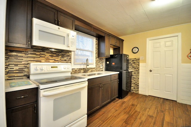 kitchen with backsplash, white appliances, dark brown cabinetry, sink, and dark hardwood / wood-style floors