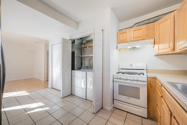 kitchen with light tile patterned flooring, independent washer and dryer, white gas range oven, and light brown cabinetry