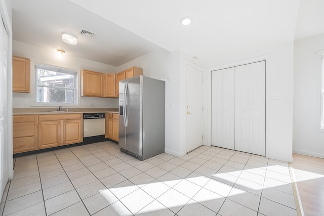 kitchen featuring stainless steel fridge, light brown cabinetry, sink, light tile patterned floors, and dishwasher