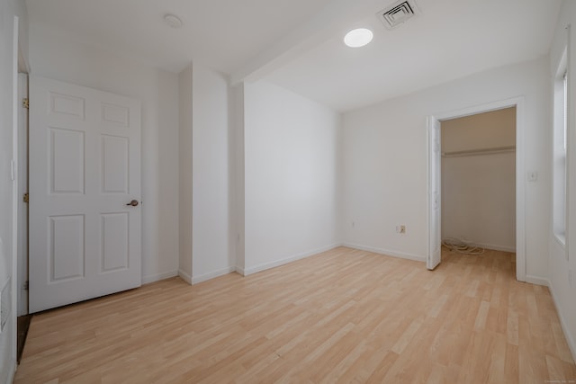 unfurnished bedroom featuring a closet, a walk in closet, and light hardwood / wood-style flooring