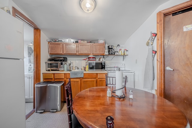 kitchen with vaulted ceiling, sink, and white appliances