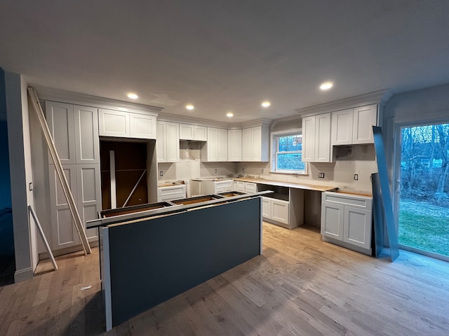 kitchen with white cabinets, a center island, and light hardwood / wood-style flooring