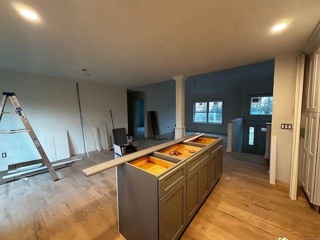 kitchen with a kitchen breakfast bar, ornate columns, and light hardwood / wood-style floors