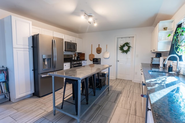 kitchen featuring white cabinetry, sink, appliances with stainless steel finishes, and dark stone counters