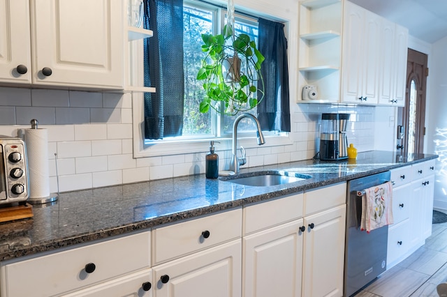 kitchen with dishwasher, white cabinetry, dark stone countertops, and sink