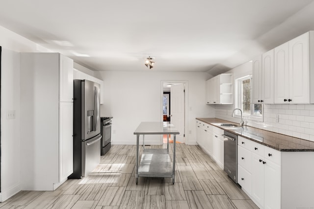 kitchen with white cabinetry, dark stone countertops, stainless steel appliances, and decorative backsplash