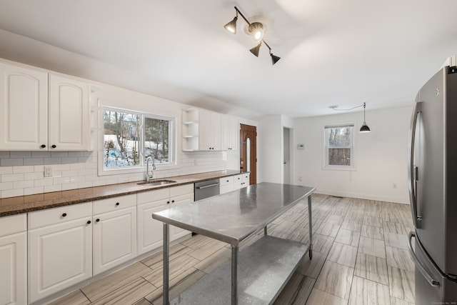 kitchen featuring appliances with stainless steel finishes, sink, white cabinets, hanging light fixtures, and tasteful backsplash