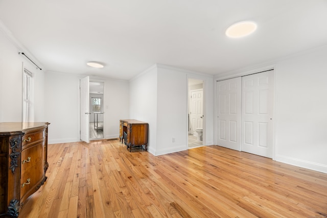 interior space with ornamental molding, light hardwood / wood-style floors, a closet, and connected bathroom