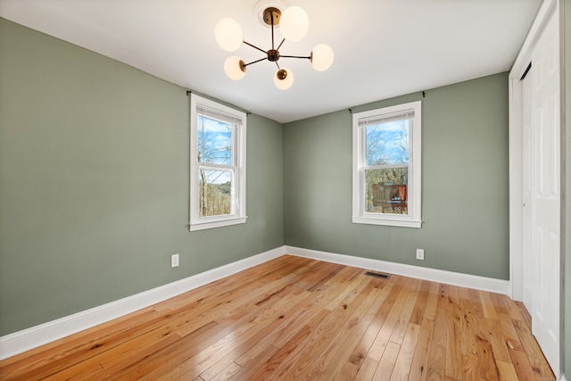 unfurnished room featuring light wood-type flooring and a notable chandelier