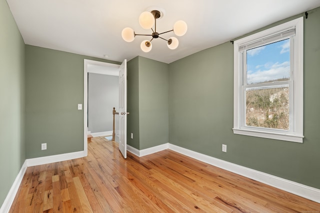 empty room with light wood-type flooring and an inviting chandelier