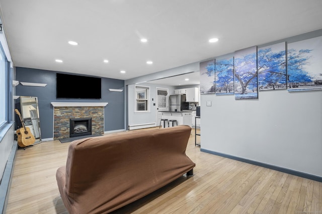 living room featuring a baseboard heating unit, a fireplace, and light hardwood / wood-style floors