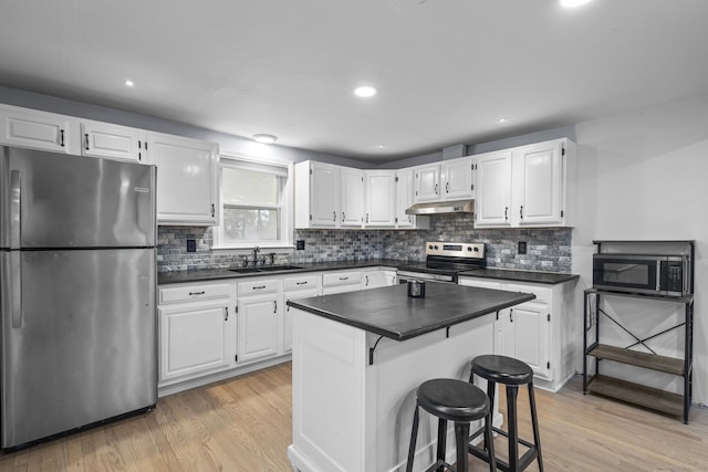 kitchen featuring appliances with stainless steel finishes, white cabinetry, sink, backsplash, and light wood-type flooring