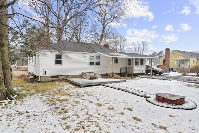 snow covered rear of property with a fire pit