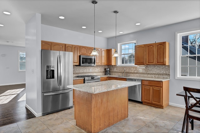 kitchen featuring appliances with stainless steel finishes, a kitchen island, hanging light fixtures, and a healthy amount of sunlight