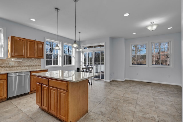 kitchen featuring backsplash, light stone counters, decorative light fixtures, dishwasher, and a kitchen island