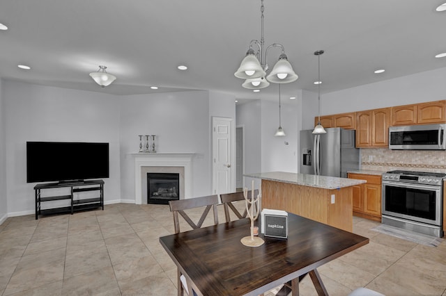 kitchen with tasteful backsplash, stainless steel appliances, an inviting chandelier, a center island, and hanging light fixtures