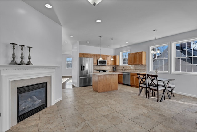 kitchen featuring a kitchen island, a healthy amount of sunlight, decorative light fixtures, and appliances with stainless steel finishes